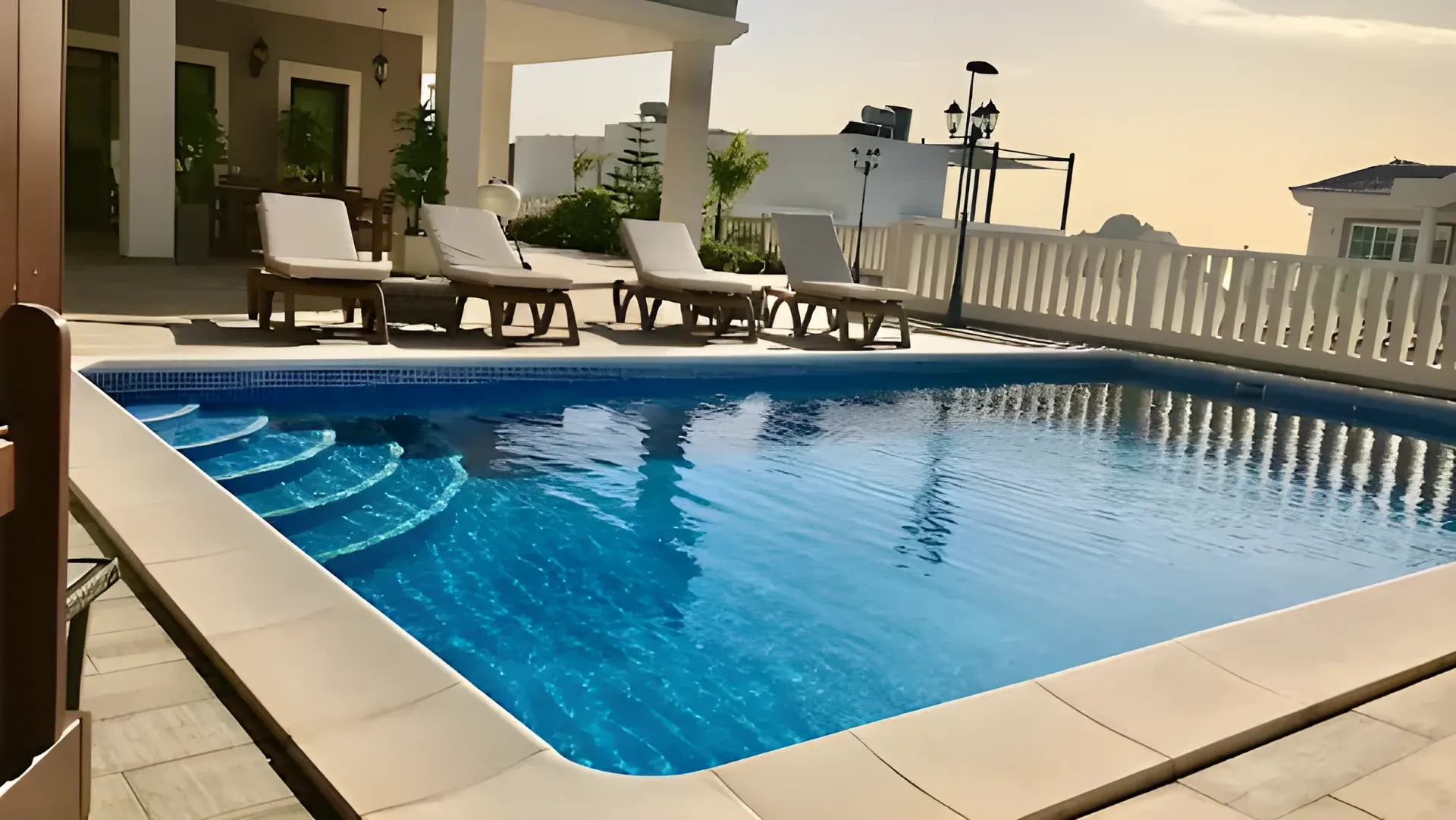 Piscina privada de Villa Jensen al atardecer, con tumbonas y vistas al mar
