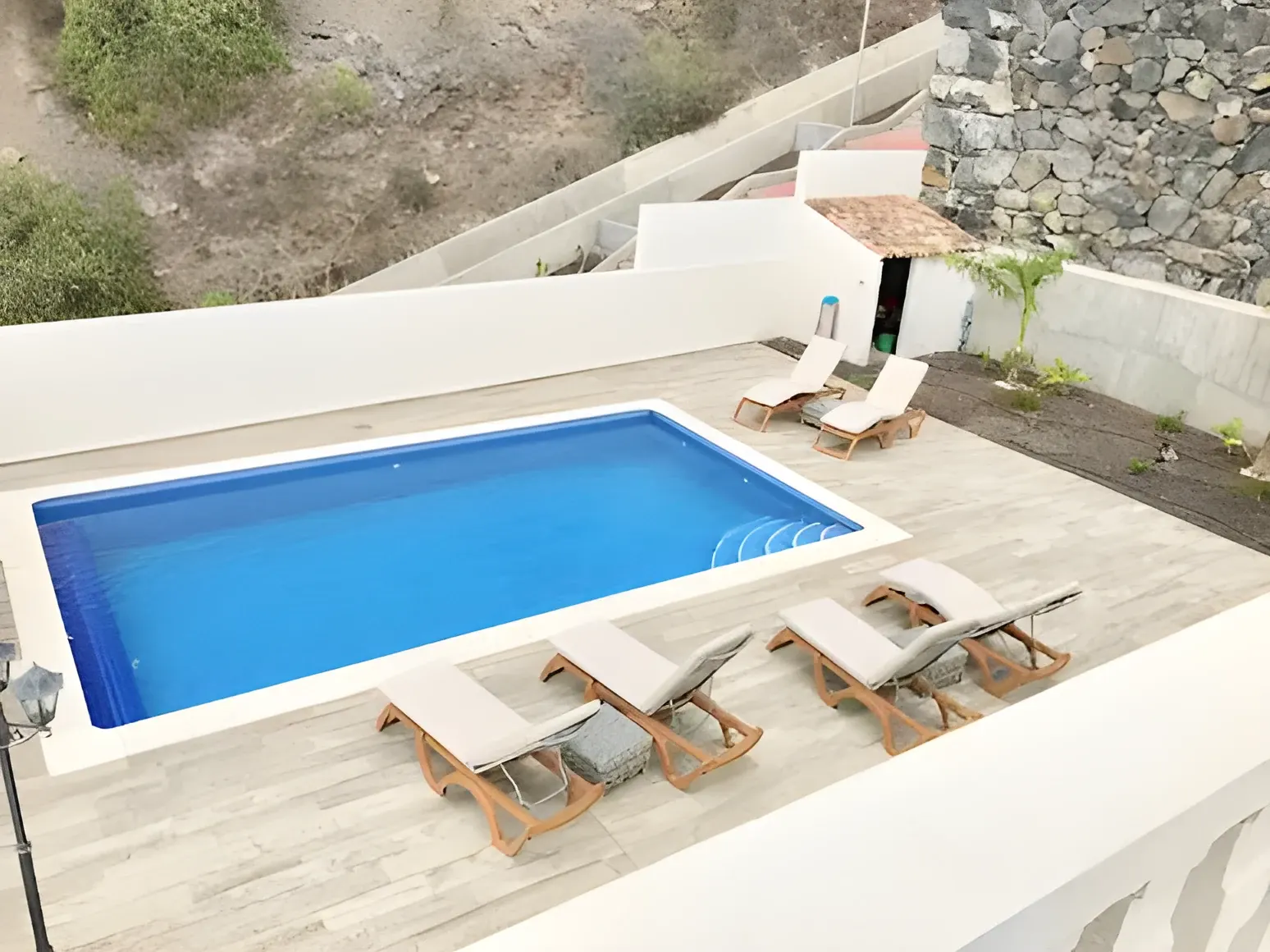 Piscina rectangular con tumbonas de madera vista desde arriba