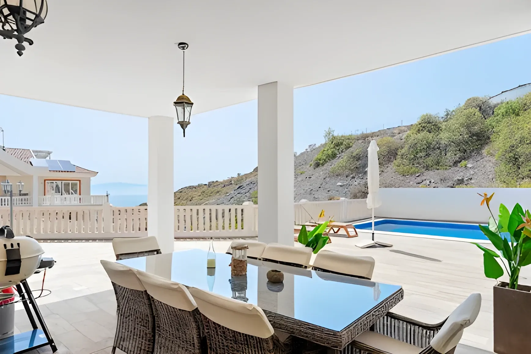 Porche cubierto con mesa exterior y vistas a la piscina